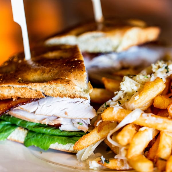 A turkey club sandwich with bacon and lettuce, served with a side of french fries.