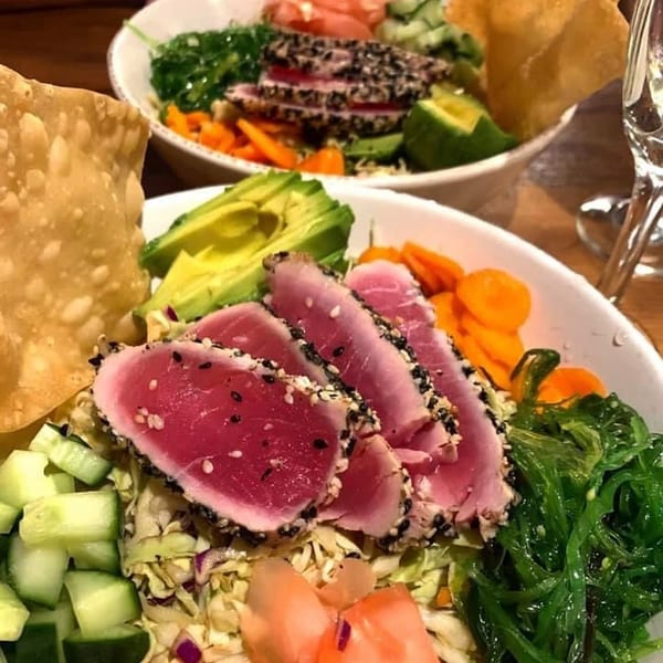 Two bowls of sesame-crusted tuna poke with avocado, seaweed, and wonton chips at Unwined Kitchen & Bar.