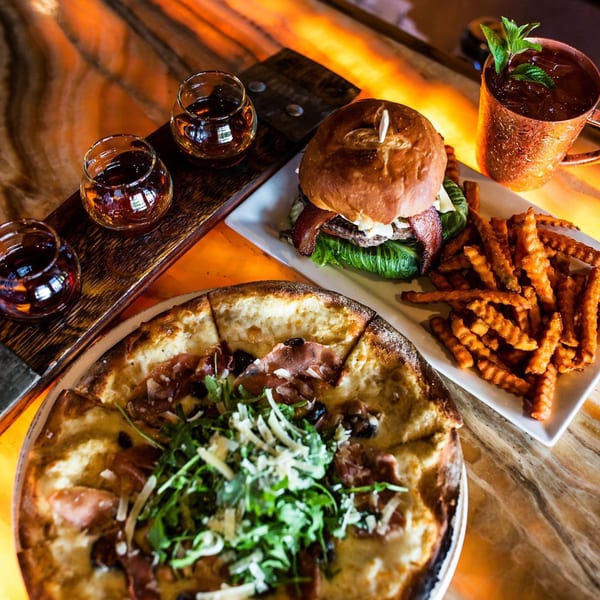 Unwined Kitchen & Bar's pizza, burger with fries, whiskey flight, and a Moscow Mule.