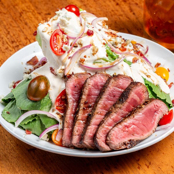 Unwined Kitchen & Bar's wedge salad with sliced steak, blue cheese, bacon, tomatoes, and red onion.