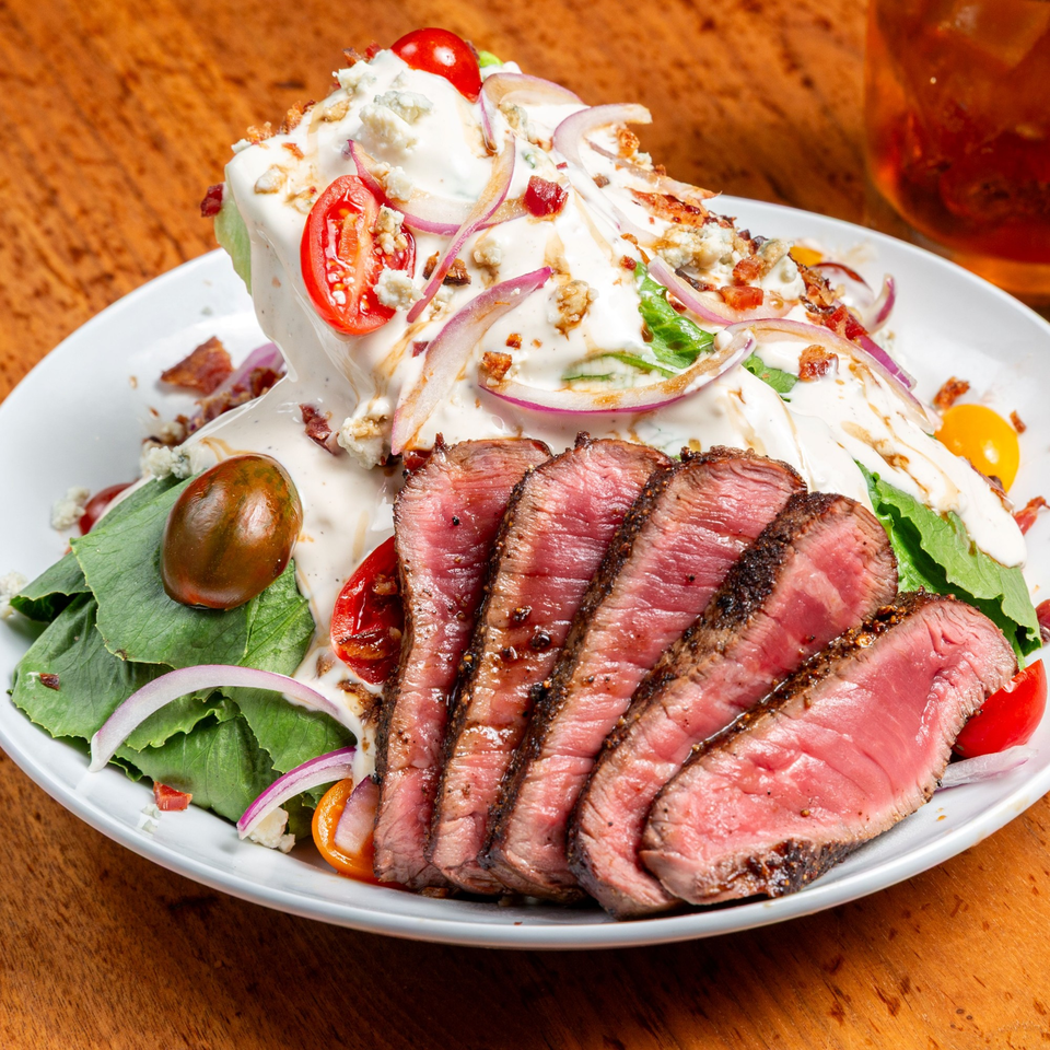 Unwined Kitchen & Bar's wedge salad with sliced steak, blue cheese, bacon, tomatoes, and red onion.